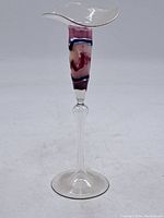 Full side view of the tall slender glass bud vase showing the clear base and stem with the multi-color body and flared rim.