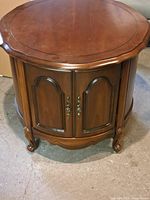 Front view of the closed mahogany console table door and carved legs.