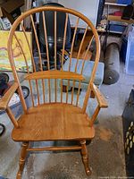 Full front view of oak rocking chair showing spindle back and armrests.