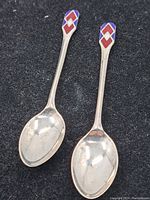 Pair of silver teaspoons with enameled handles showing their full form and design.