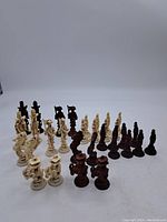 Three-quarter view showing both ivory and dark brown resin chess pieces arranged in formation, highlighting the number and design.