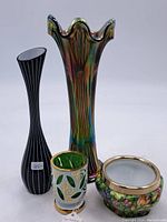 Four vintage and antique vases and candleholders grouped together on white surface, showing colors and shape variety.