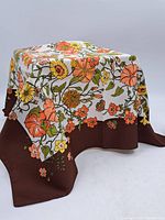 Silk scarf draped over a box, showing the overall floral pattern with brown border.