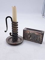 Photo showing both the wrought iron candle holder with spiral coil design and the rectangular matchbox holder side by side