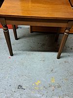 Front view of rectangular walnut piano bench showing top and legs.