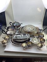 Wide view of full set showing large trays, pots, divided dish, cups, and small bowls with visible tarnish.