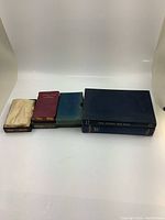 Group of various vintage and antique books, some in slipcases, displayed against white background.