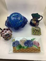 Overview of six decorative collectible vintage items including art glass, ceramics, and a glass tray with floral design.