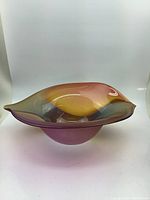 Side view of hand blown glass bowl showing flowing colors and wide flared rim with curving organic shape.
