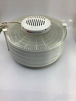 Side view of the white Nesco food dehydrator showing stackable trays and vents on the top central heating unit.