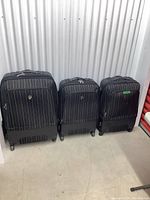 Set of three HEYS black striped soft luggage pieces side by side showing the size difference and condition.