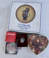 M.J. Hummel 1983 Annual Plate box, Lilian Vernon box, silver-tone ornament in felt box, and heart-shaped Christmas tin shown together