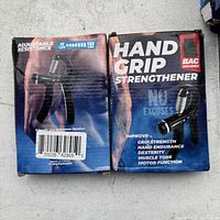 Front and back of the product box showing the hand grip strengthener with adjustable resistance from 11 to 132 lbs and included carrying bag.