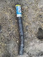 Rolled black hexagonal netting lying on pavement, showing the full roll and plastic packaging.