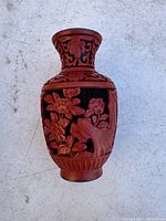 Full front view of vintage Chinese cinnabar or resin vase with carved floral design and decorative neck.