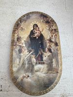 Full front view of the oval decorative plate showing Virgin Mary holding baby Jesus and surrounded by angels with a gold floral border.