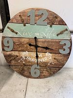 Front view of the round wooden wall clock showing the full face with numbers, rope accents, and text.