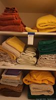 Shelves with assorted folded towels in multiple colors including burnt orange, yellow, green, beige, and cream.