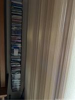 Tall stack of many CDs in jewel cases, varying titles and genres