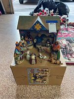 Full view of the nativity set arranged on cardboard box with stable and all figurines visible.