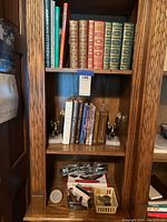Photo of bookshelf showing various leather-bound classic books, paperbacks, and decorative eagle bookends