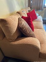 Side view of golden-beige couch with pillows, showing fabric texture and armrest shape.