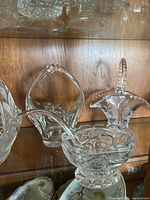 Photo showing two different etched crystal baskets with distinct handles and patterned etching.