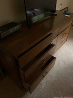 Angle view showing top surface and front with several drawers partially open, displaying wood grain drawers with metal handles.