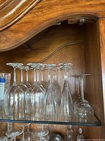 Wine goblets on a glass shelf inside a wooden cabinet, 8 goblets visible.