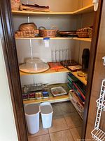 Pantry shelves with various kitchen items including baskets, Lazy Susan, metal rack, plastic bins, and boxes of Swiffer cloths