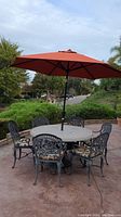 Full view of patio table with six chairs and umbrella set up outdoors