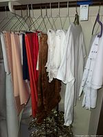 Multiple colored tablecloths and white fabric pieces hanging on various hangers in a closet.