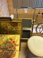Photo showing the rolling metal cart holding the set of 4 folding TV trays with floral wooden tops and gold edges arranged upright.