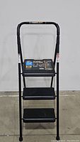 Full front view of the Werner 3-step foldable steel step stool ladder with black finish and safety rail.