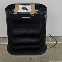 Front view of the black Honeywell HEPA air purifier with taped instruction sheet on top.