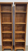 Pair of tall wooden bookcases shown side by side, each with five shelves and a natural wood finish.
