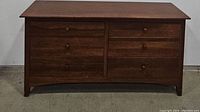 Front view of the dresser showing all drawers closed, highlighting the dresser's wood finish and style.