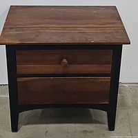 Front view of the Ethan Allen nightstand showing cherry wood top and drawer fronts with black legs and frame, including wooden knob handles.