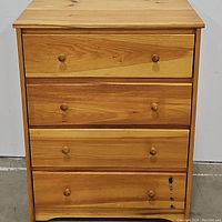 Front view of oak dresser showing four drawers with round wooden knobs, with some visible dark marks on bottom drawer.