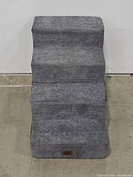 Front view of gray fabric-covered pet stairs showing the step surfaces and fabric texture.