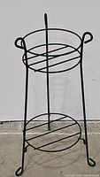 Front view of the 2-tiered iron plant stand showing circular shelves and tubular frame.