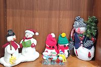 Photo of all 7 plush holiday figures: four snowmen with various hats and scarves, and three small birds with hats and scarves.