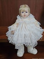 Vintage porcelain baby doll with blue eyes, white lace dress and white shoes