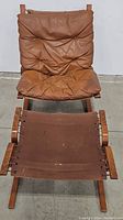 Siesta lounge chair with attached brown leather cushions and ottoman with fabric top, shown from front.