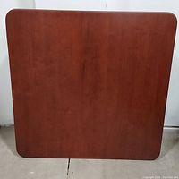 Top view of cherry wood card table with smooth surface and rounded edges.