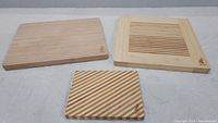 Three bamboo cutting boards displayed flat: two large rectangular ones and one small square, all branded Island Bamboo with bamboo logos.