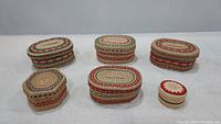 Photo showing six nesting baskets with lids in various sizes and Christmas-themed colors, arranged in two rows on a white surface.