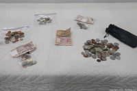 Overview of mixed loose coins and paper banknotes from various countries arranged on a white quilted surface