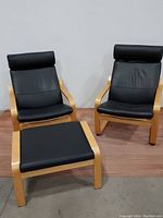 Two IKEA POANG chairs and matching footstool with black vinyl cushions and light wood frames seen from an angle.