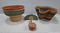 Full lot display of two large colorful baskets, smaller lidded basket, and fan on white backdrop